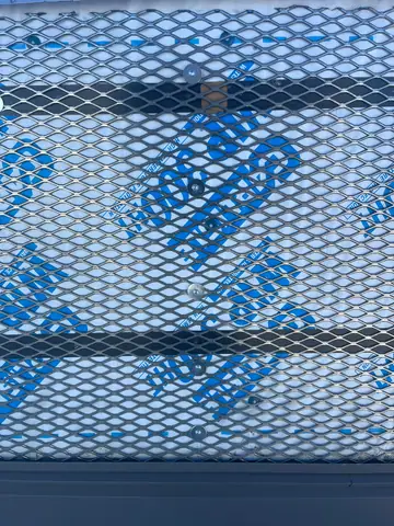 Expanded steel security mesh, fastened over the barrier (Rooftop Screen Wall & Security Mesh, Denver Tech Center)